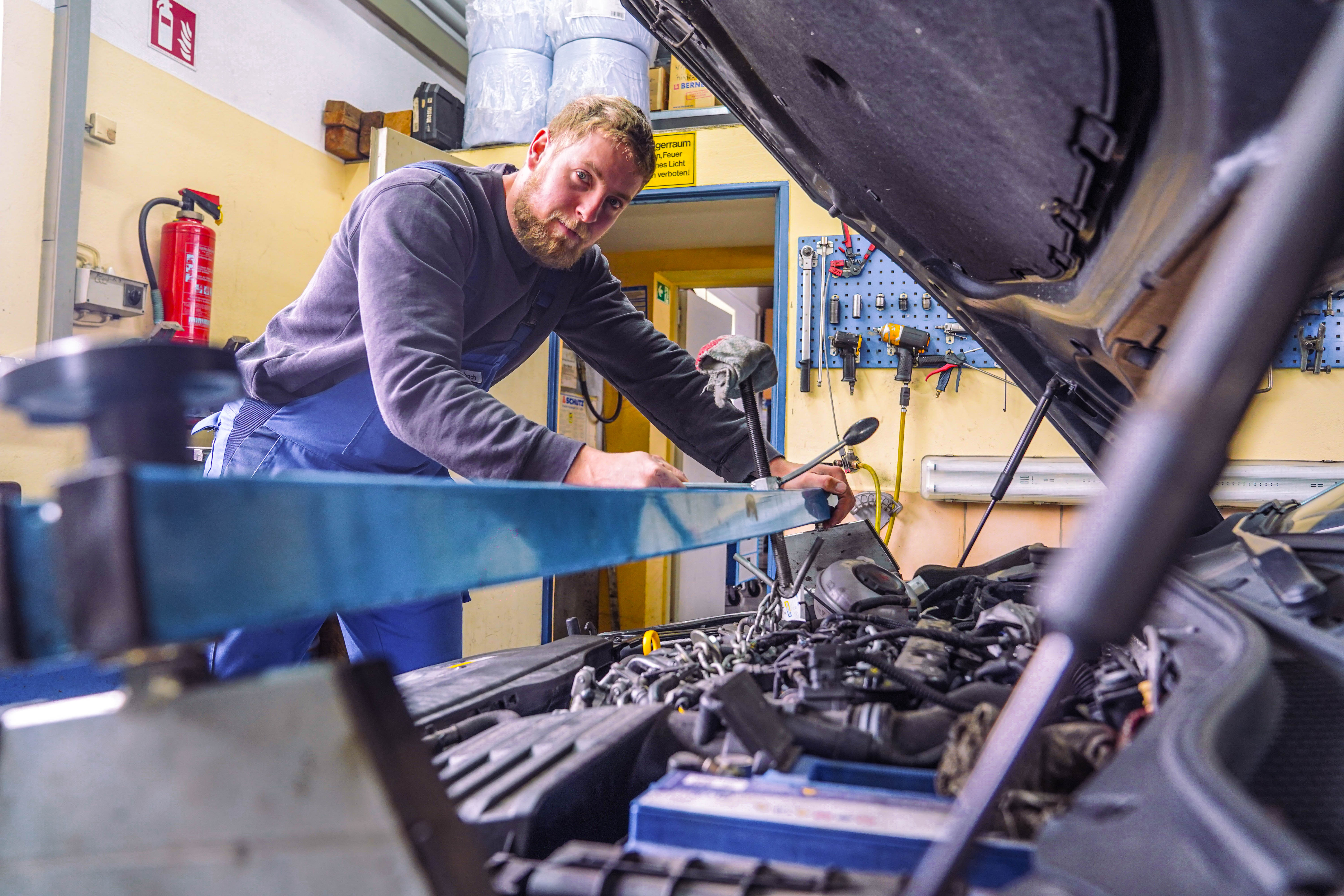 Mechatroniker schaut bei der Arbeit am Motor in die Kamera