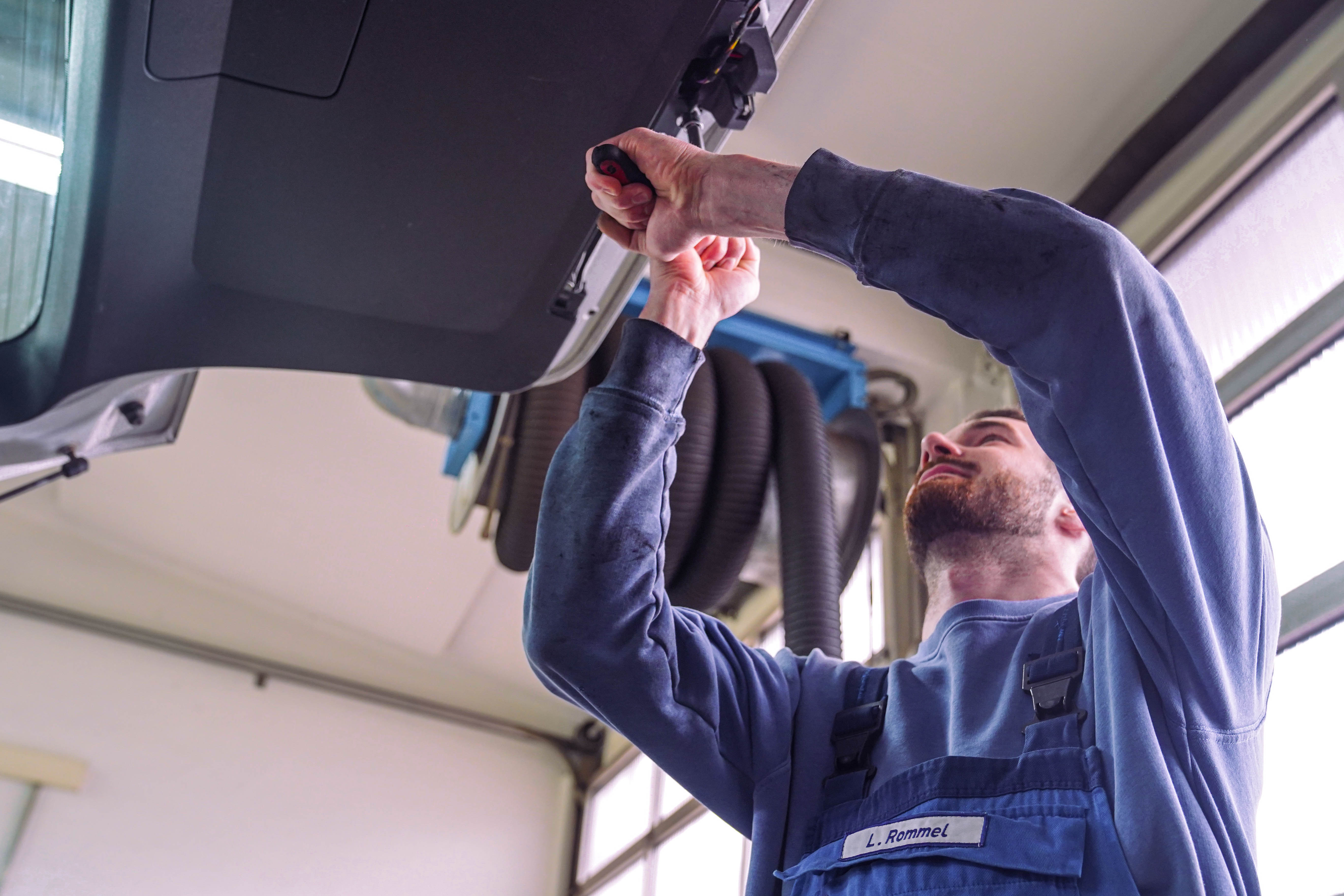 Mechatroniker arbeitet an einer Heckklappe, Blickwinkel von unten